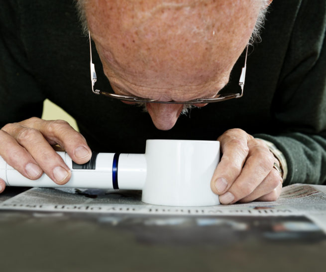 Senior liest mit Lupe