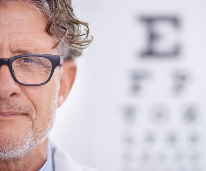 Mann mit Brille vor Sehtesttafel